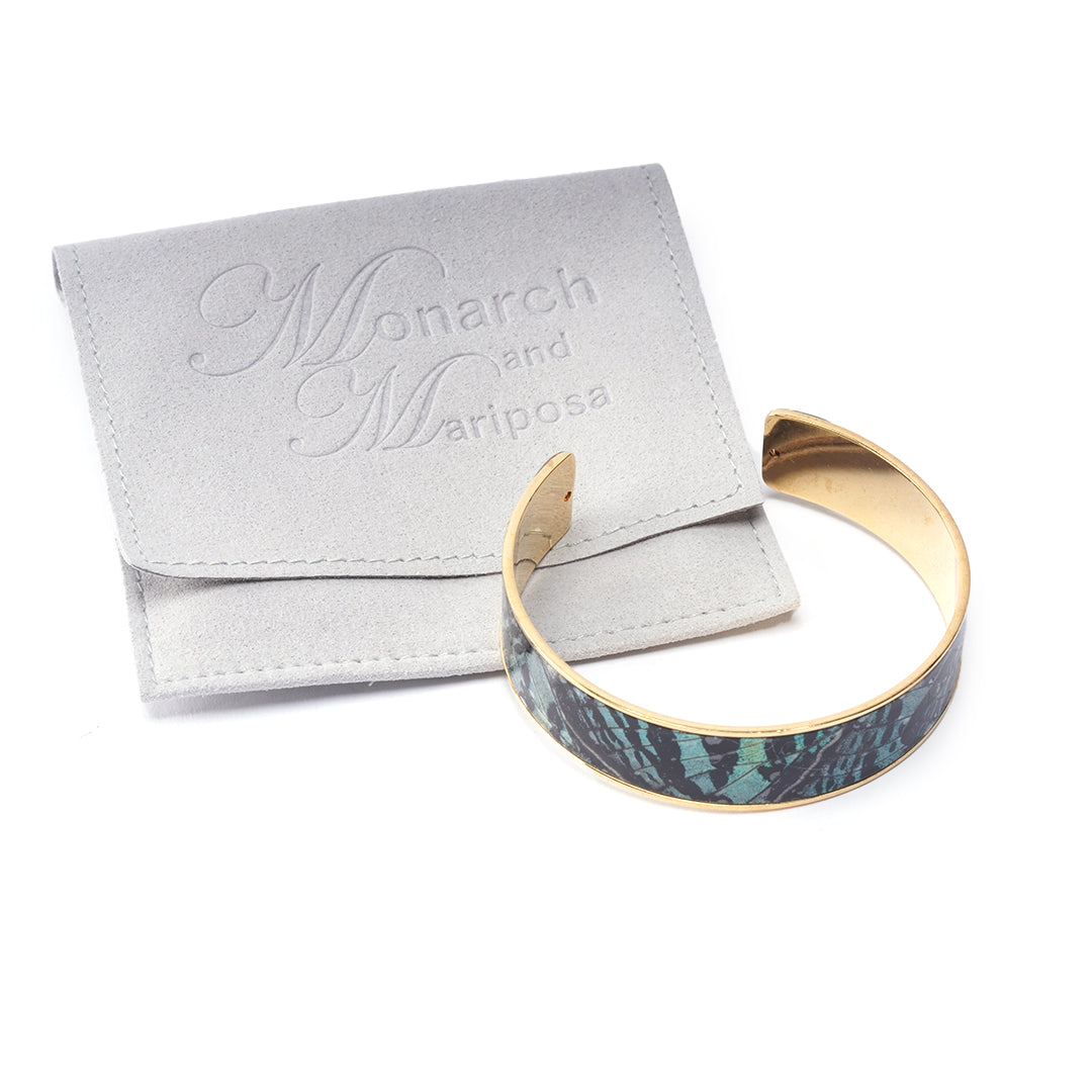 Product photo of the Midnight butterfly cuff bracelet, shown with Monarch and Mariposa gray jewelry pouch.